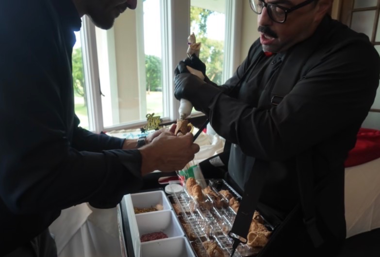 A cannoli being filled fresh for a guest